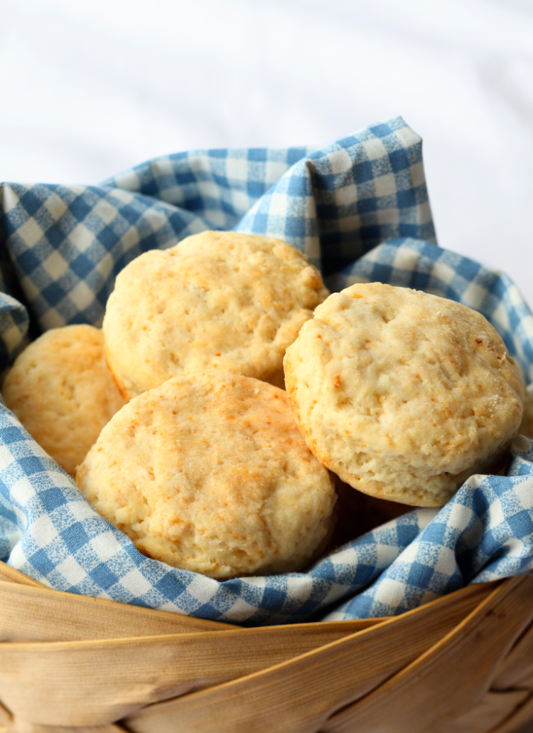 fluffy biscuits in a basket with blue gingham towel