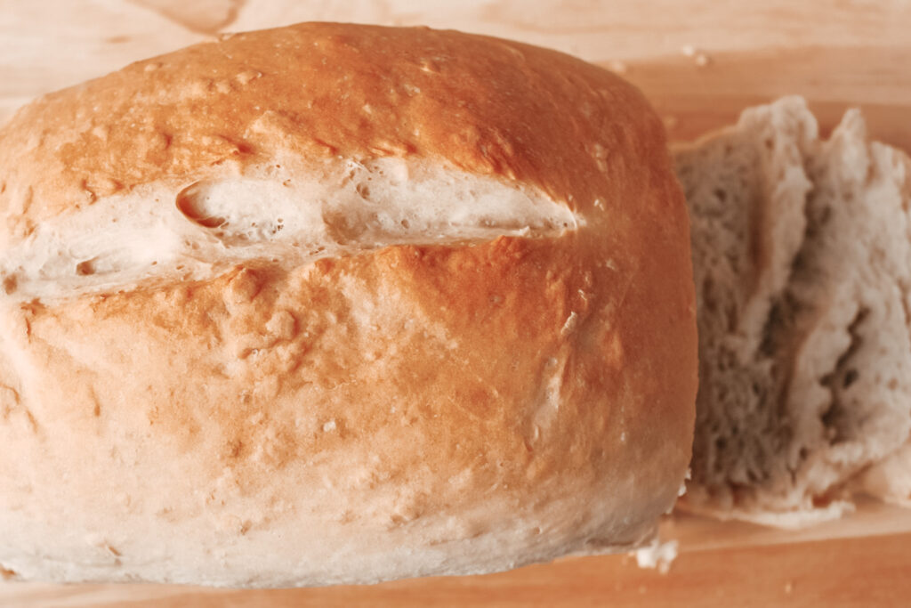 Golden Fresh Baked Loaf of Bread on Wood Surface